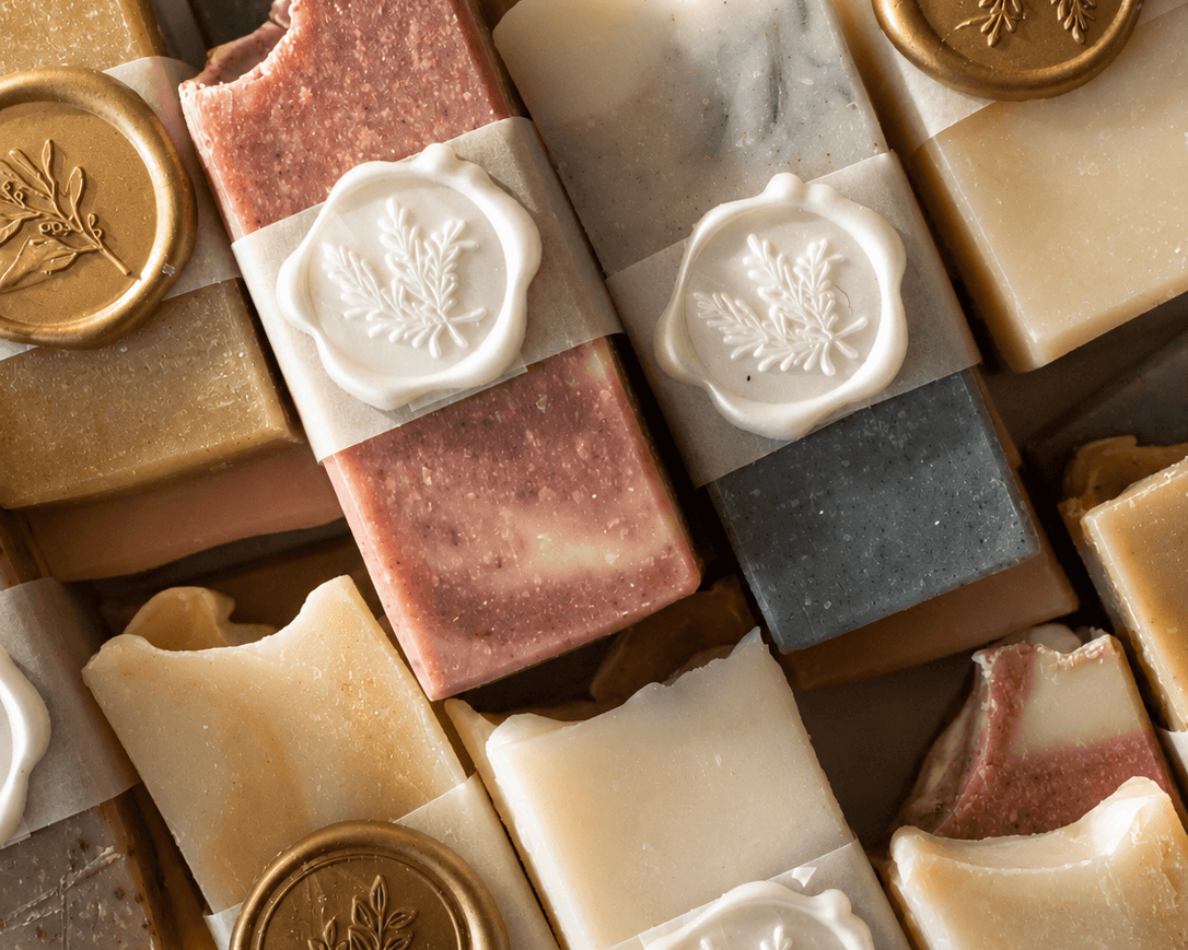 Assorted bars of soap with decorative seals on a textured surface