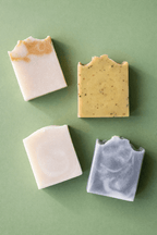 Four different bars of artisan soap on a green background